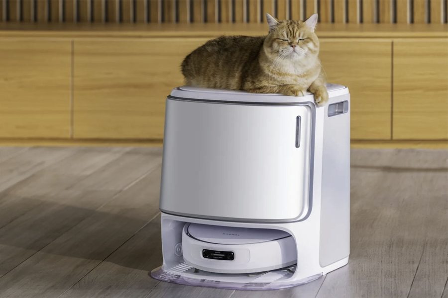 A ginger cat dozing on top of the Narwal Freo Z Ultra dock, the robot vacuum parked underneath